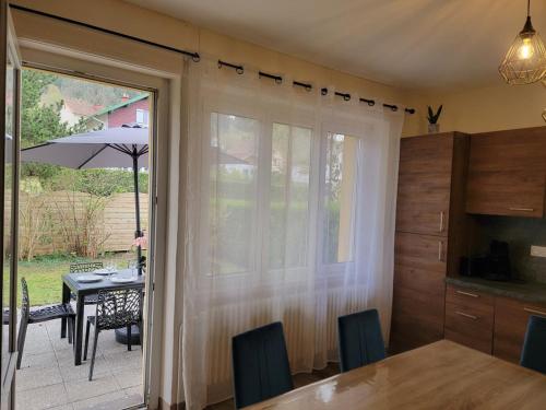 une cuisine et une salle à manger avec une porte coulissante en verre donnant sur un patio dans l'établissement Chez Carine et Jonathan, à Gérardmer