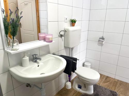 a white bathroom with a sink and a toilet at Csorgó Vendégház in Felsődobsza