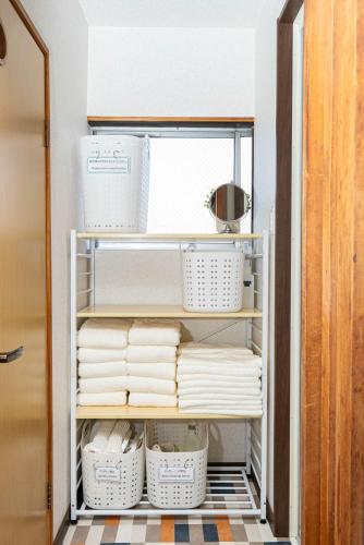 a closet filled with lots of white dishes and baskets at MOMOYA tsudoi in Okayama