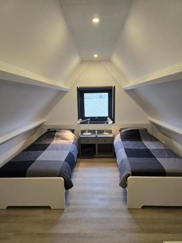 two beds sitting in a room with a window at Strandhuisje achter de duinen. in Julianadorp