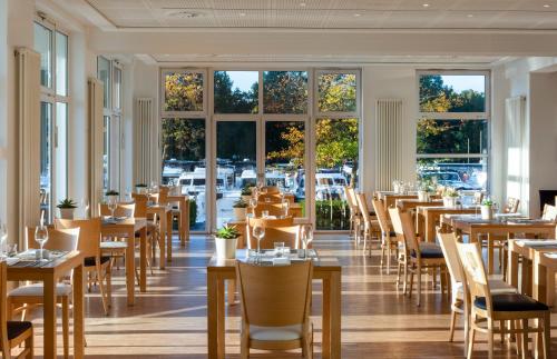 a restaurant with tables and chairs and windows at Precise Resort Marina Wolfsbruch - Hotel in Rheinsberg