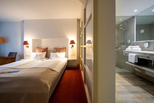 a bedroom with a large bed and a bathroom at Golfhotel Gut Apeldör in Hennstedt
