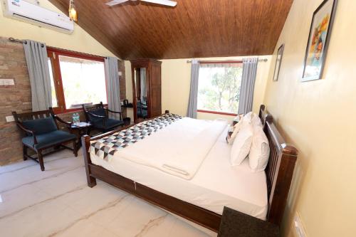 a bedroom with a bed and a chair and windows at The Sky Imperial Jungle Camp Resort in Kumbhalgarh