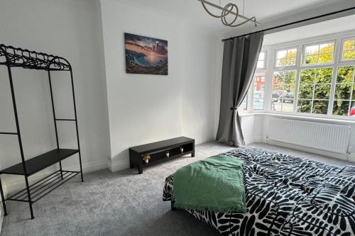 a bedroom with a black and white bed and a window at Manchester City Oasis - Spacious 5 Bedroom House in Manchester