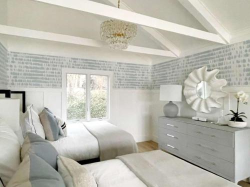 a bedroom with two beds and a window and a mirror at Wequassett Resort and Golf Club in East Harwich