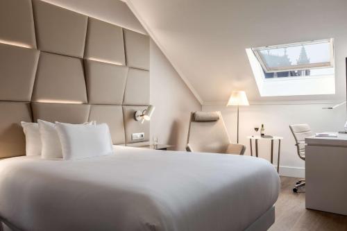 a hotel room with a large white bed and a window at NH Collection Brussels Grand Sablon in Brussels