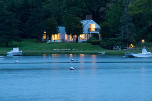 a house on the shore of a lake with boats in the water at Wequassett Resort and Golf Club in East Harwich