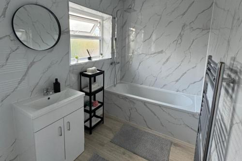 a bathroom with a sink and a tub and a mirror at Manchester City Oasis - Spacious 5 Bedroom House in Manchester
