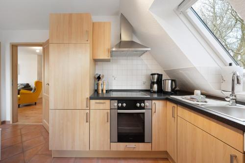 una cucina con armadi in legno, lavandino e finestra di Ferienwohnung Auszeit a Nordstrand