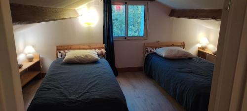 deux lits dans une petite pièce avec une fenêtre dans l'établissement Les treilles de Provence, Gîte la glycine, à Villeneuve-lès-Avignon