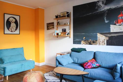- un salon avec un canapé bleu et des murs orange dans l'établissement Bright T2 just outside the City of Light, à Aubervilliers