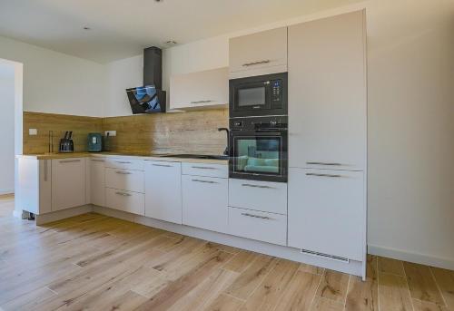 une cuisine avec des armoires blanches et un micro-ondes dans l'établissement Casa Mia-Appartement Standing-Monticello, à Monticello