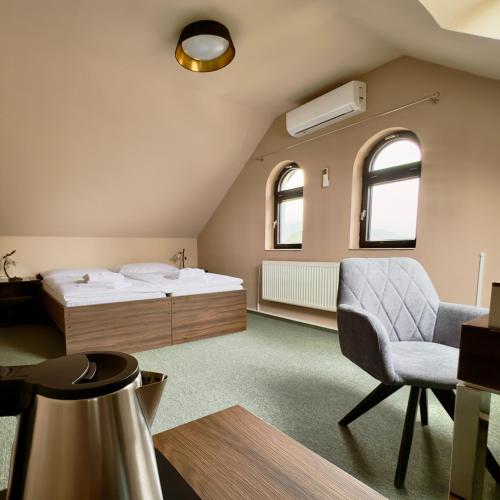 a bedroom with a bed and a chair at Hotel Zelený dům in Dolní Poustevna