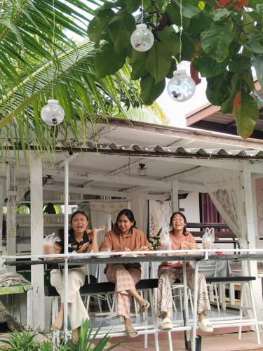 three women sitting on the porch of a house at Maidok Homestay(ไม้ดอกโฮมสเตย์) in Ban Pak Ba Ra
