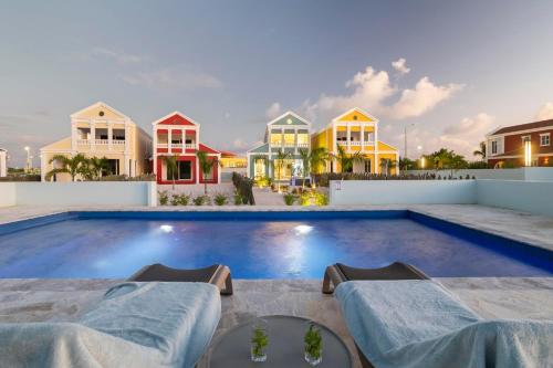 a swimming pool with two massage tables in front of houses at Casa Blue Marlin (begane grond) in Kralendijk