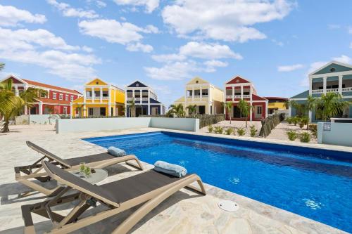 a swimming pool with two lounge chairs and houses at Casa Blue Marlin (1e verdieping) in Kralendijk