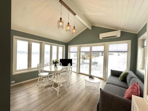 Una sala de estar con un sofá, una mesa y sillas. en Victoria lakefront cabin in Lyseren Strandpark, en Omberg