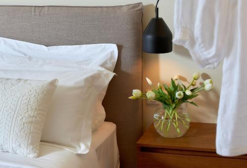 a vase of flowers on a night stand next to a bed at The NooK -Luxury living at the edge of tranquility in Heraklion