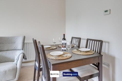 a dining room table with two chairs and a bottle of wine at Last-Minute Secure l Sleeps Up to 8 l 2 Bedroom Apt By Capital Retreats Short Lets & Serviced Accommodation London With Balcony, Free WiFi in Colindale