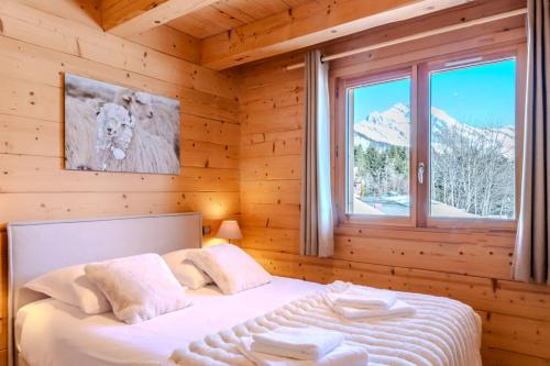 a bedroom with a bed in a log cabin at Slow Chalet Mont Real - Le Grand Bornand - 3km from slopes Chinaillon in Le Grand-Bornand
