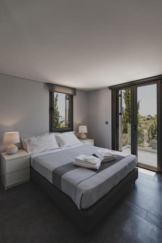 a large white bedroom with a large bed and windows at St Aims by Bluesites in Porto Heli