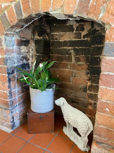 a statue of a bird standing next to a brick oven at Old country cottage in Ashbourne