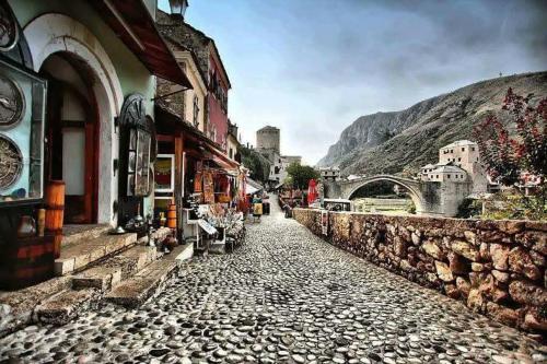 a cobble stone street with buildings and a bridge at Hostel Mirror in Mostar
