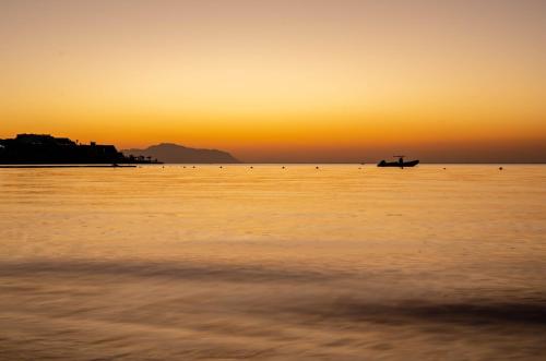 a sunset over the ocean with a boat in the water at Park Regency Sharm El Sheikh Resort in Sharm El Sheikh