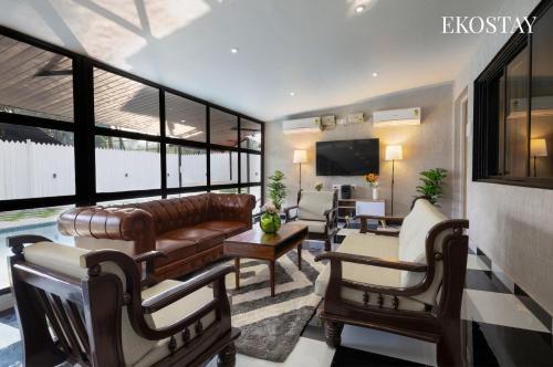 a living room with a leather couch and a television at EKOSTAY - Hazelnut Villa in Alibaug