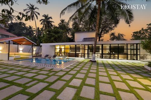 a house with a palm tree in front of it at EKOSTAY - Hazelnut Villa in Alibaug
