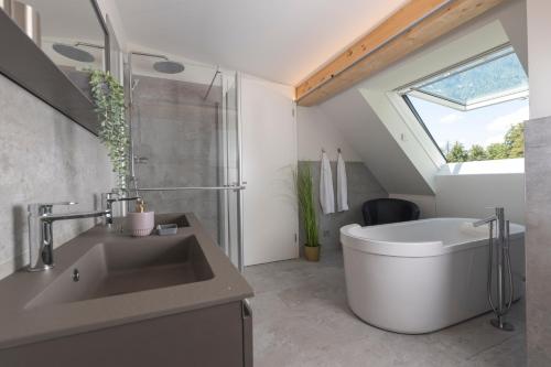 ザンクト・ヴォルフガングにあるSEE & THE CITY apartmentsのバスルーム(大きな白いバスタブ、シンク付)