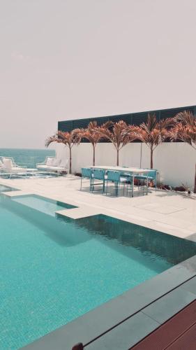 a swimming pool with chairs and a table and palm trees at 2 - BLUE WORLD - Al Dana Villas in Fujairah