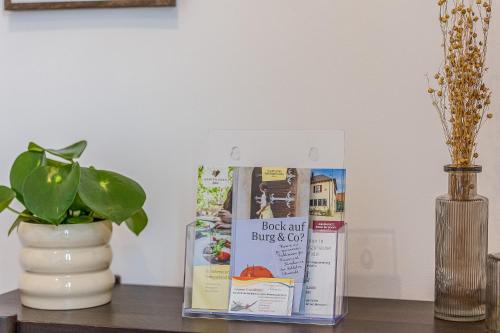 a book and a vase on a table with a plant at Im Herzen der Pfalz - Urlaub in der Rebenkoje in Ruppertsberg