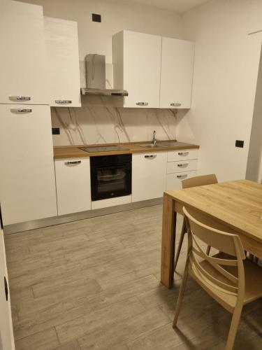 a kitchen with white cabinets and a wooden table at Appartmenti 3 TORRI in Maddaloni