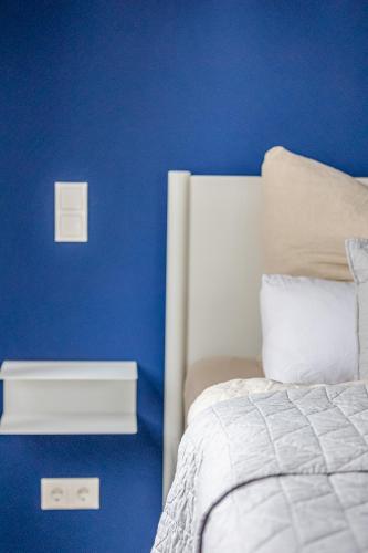 a blue bedroom with a bed and a blue wall at Im Herzen der Pfalz - Urlaub in der Rebenkoje in Ruppertsberg