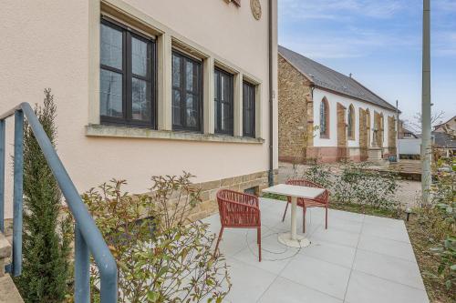 a patio with two chairs and a table and a building at Im Herzen der Pfalz - Urlaub in der Rebenkoje in Ruppertsberg