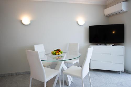 une salle à manger avec une table en verre et des chaises blanches dans l'établissement One bedroom apartment with beautiful sea view, à Cannes