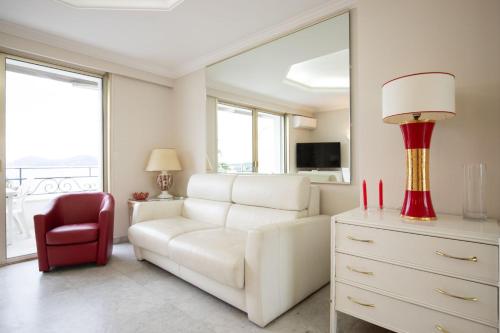 un salon avec un canapé blanc et une chaise rouge dans l'établissement One bedroom apartment with beautiful sea view, à Cannes
