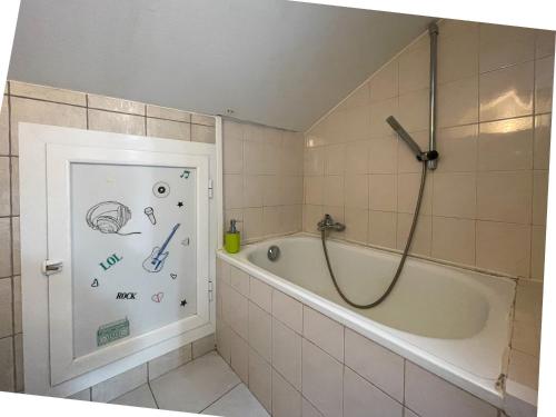une salle de bain avec une baignoire et une douche avec des dessins sur le mur dans l'établissement France, hyper centre - Wifi, AC, 2pers, à Nice