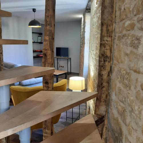 Cette chambre dispose de tables et de chaises en bois ainsi que d'un mur en briques. dans l'établissement Le Clos Fénelon, à Sarlat-la-Canéda