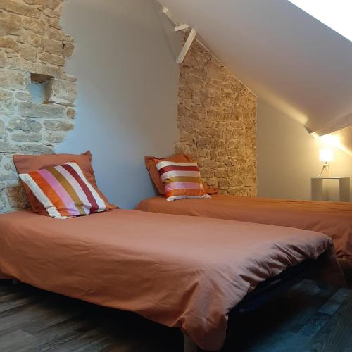 - 2 lits dans une chambre avec un mur en pierre dans l'établissement Le Clos Fénelon, à Sarlat-la-Canéda