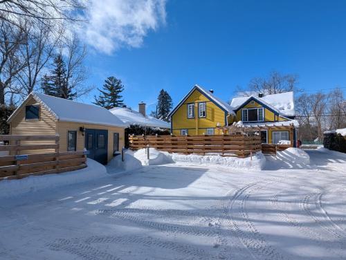 a house with a fence and a yard covered in snow at Au Saut Du Lit in Magog-Orford
