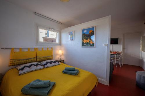 ein Schlafzimmer mit einem gelben Bett mit Handtüchern darauf in der Unterkunft Le Ptit Bois - Piscine partagée in Saint-Laurent-en-Grandvaux