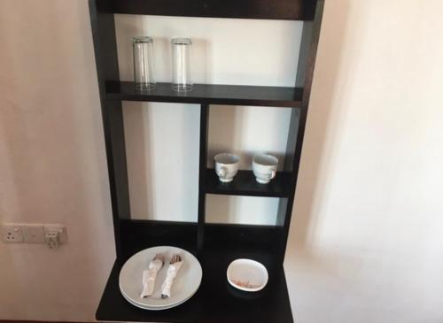 a black shelf with a plate and glasses on it at King's Lodge in Nuwara Eliya