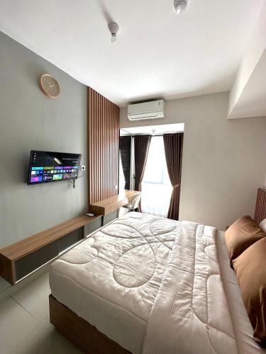 a bedroom with a bed and a flat screen tv at Barsa City by Eleanor in Seturan