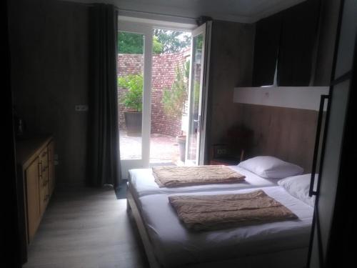 two beds in a room with a window at de Plaats Maasbree in Maasbree