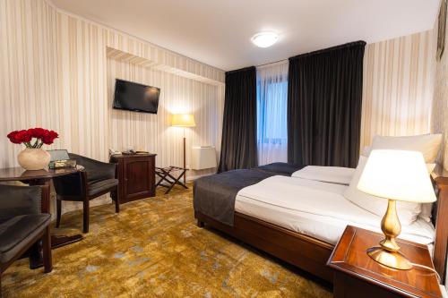 a hotel room with a bed and a desk at Hotel Brilliant Plaza in Zalău