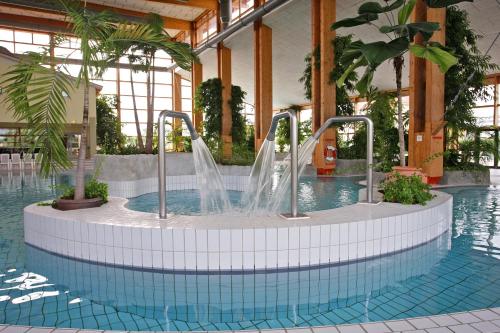 a pool with a water fountain in a building at Precise Resort Rügen Apartments & SPLASH Erlebniswelt in Sagard