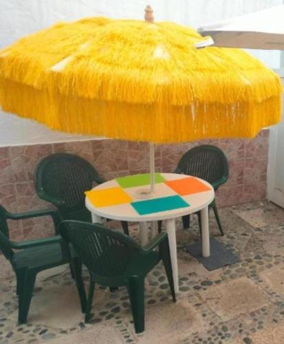 a table with chairs and a yellow covering over it at Piscina club pasito blanco in Pasito Blanco