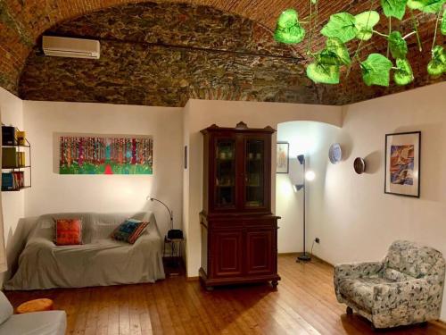 una sala de estar con un sofá y una silla en Ca' du Ventu - Cozy house with mezzanine & little garage, en Calice Ligure